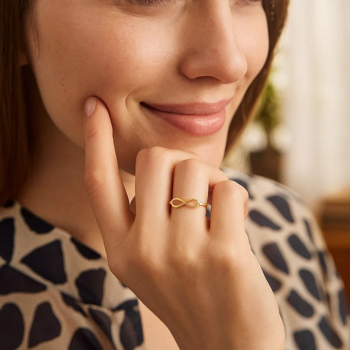 14K yellow gold polished infinity ring worn on finger, lifestyle shot at Savannah Lane Jewelry