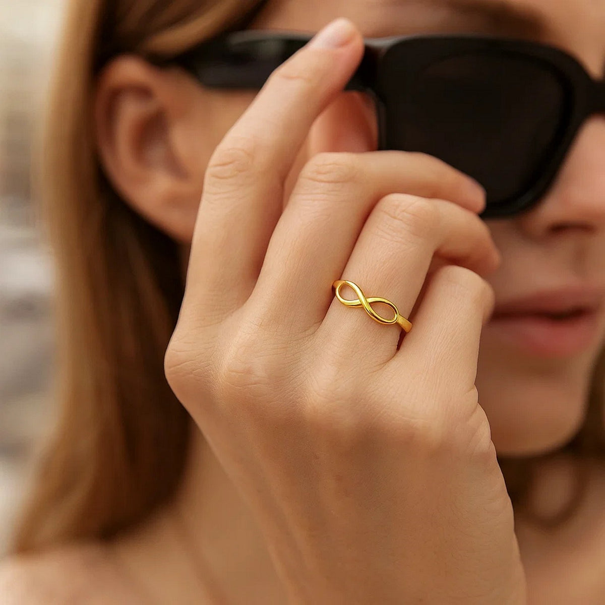 14K yellow gold polished infinity ring worn on finger, lifestyle shot at Savannah Lane Jewelry