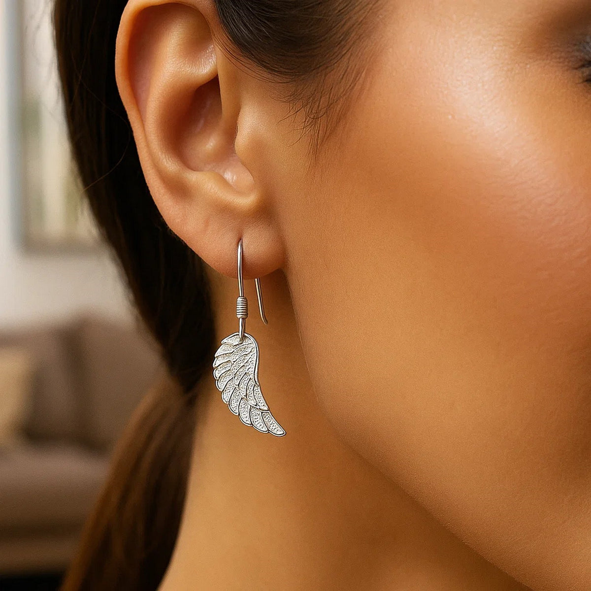 Sterling silver angel wing leverback earrings worn on model, lifestyle shot showing drop length