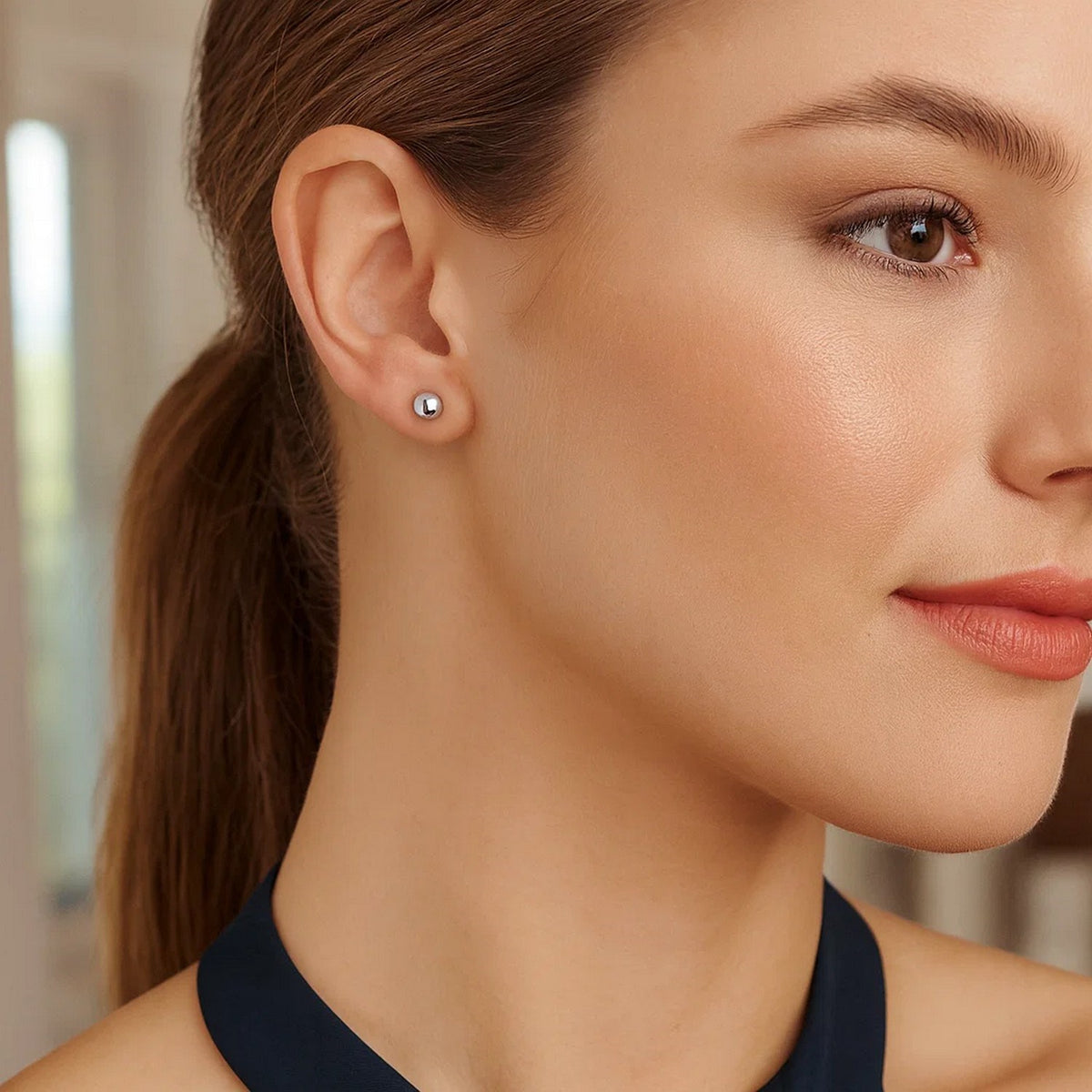 Close-up of sterling silver ball stud earring worn on ear indoor lifestyle