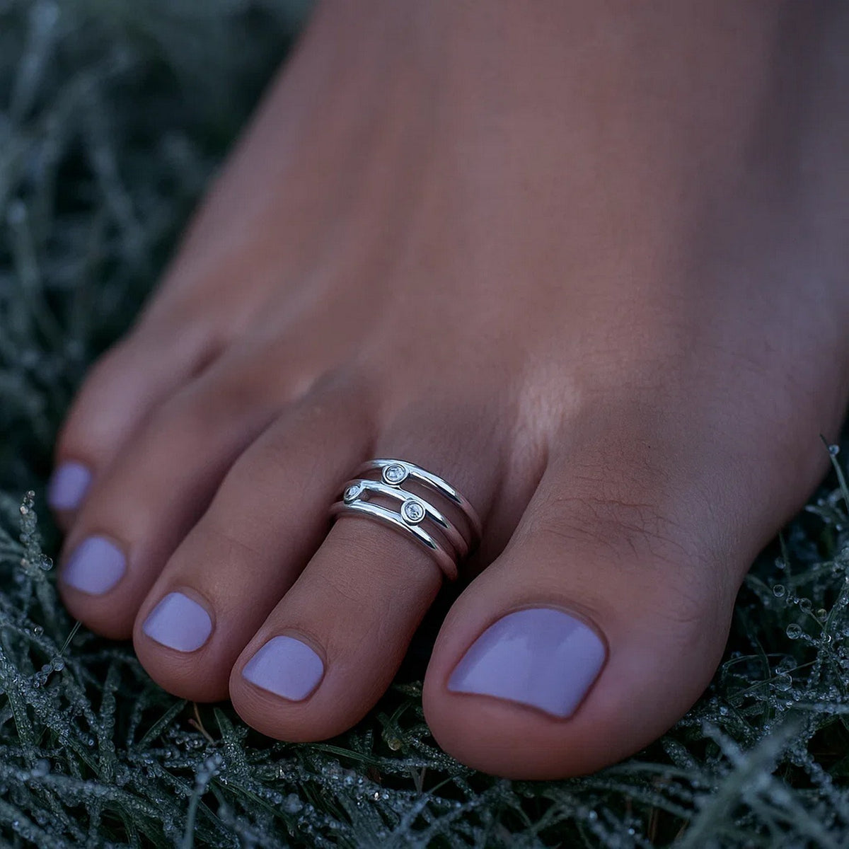 Sterling silver rhodium CZ triple line toe ring worn on foot outdoors