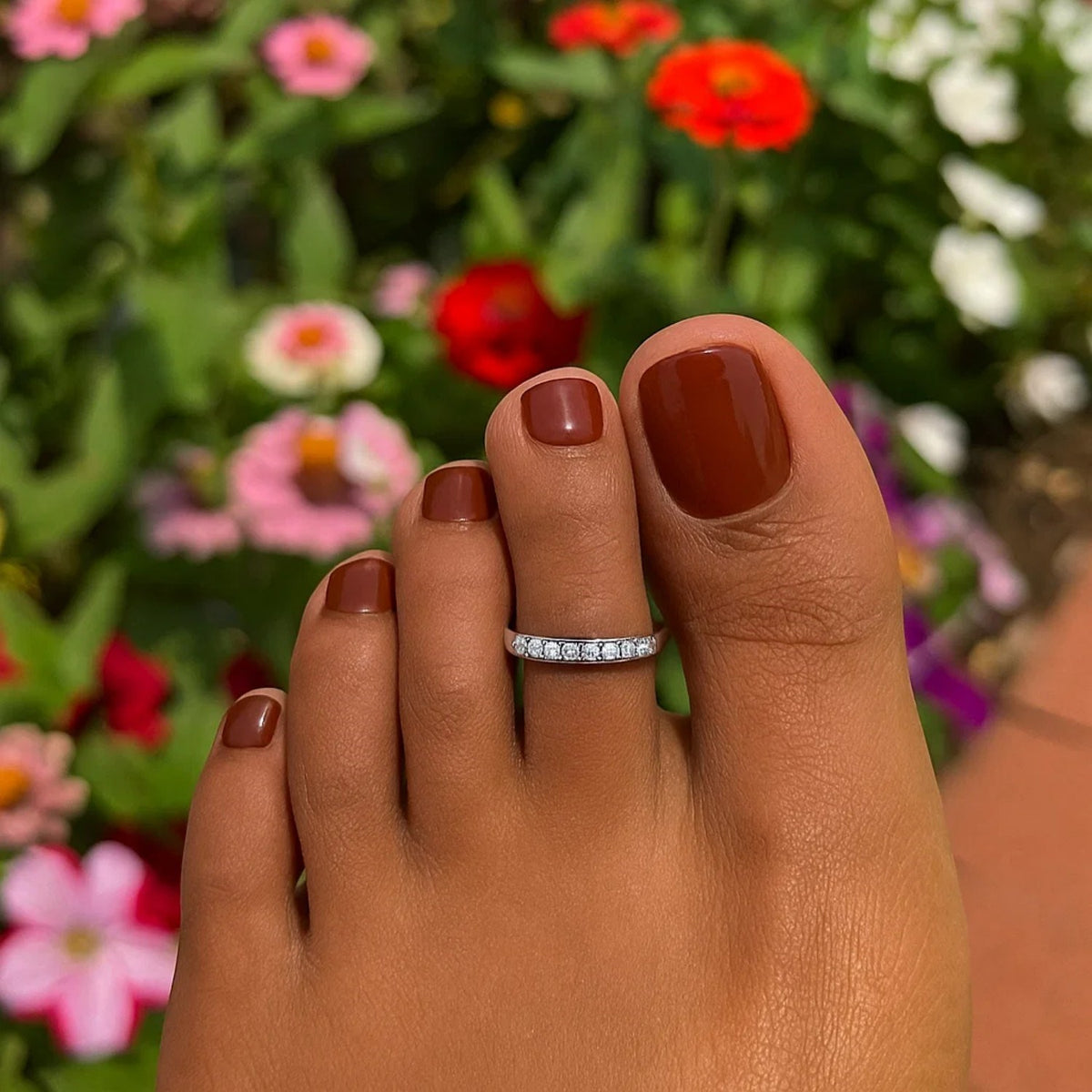 Close up view of sterling silver CZ toe ring worn on toe in grass
