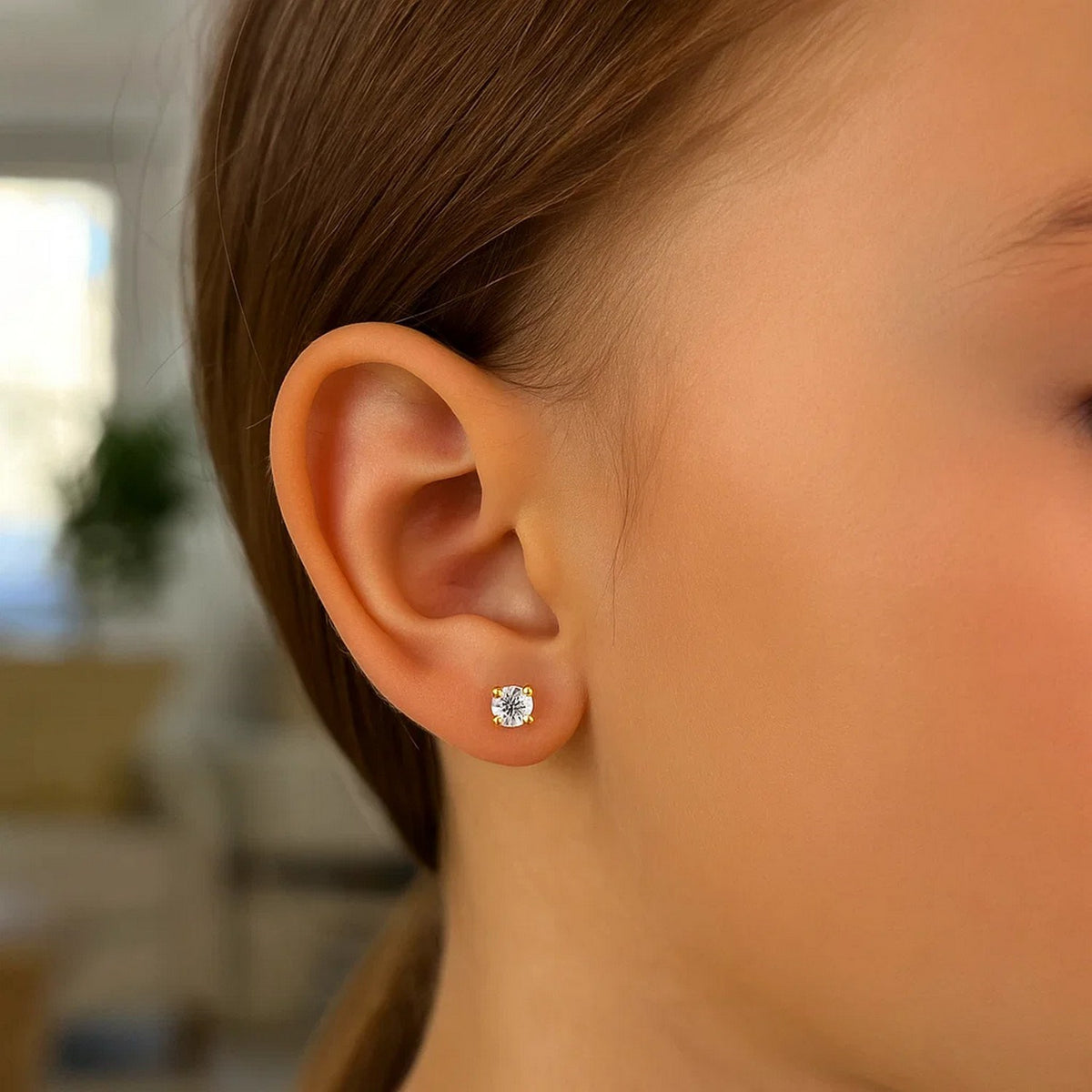 Woman wearing 14k yellow gold 2mm cubic zirconia stud earring close up view