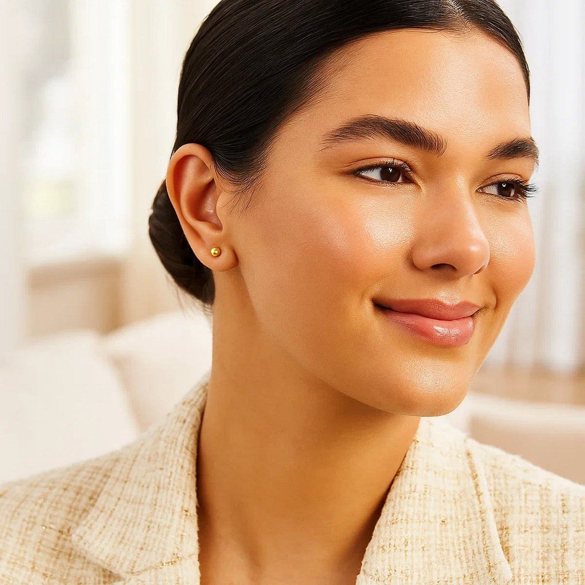 Woman wearing 10k yellow gold 4mm ball stud earring smiling in studio portrait