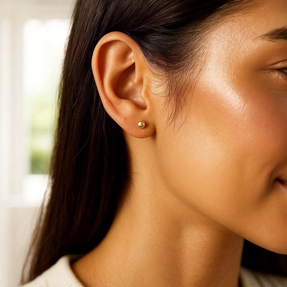 Side profile of woman wearing 10k yellow gold 4mm ball stud earring in ear lobe