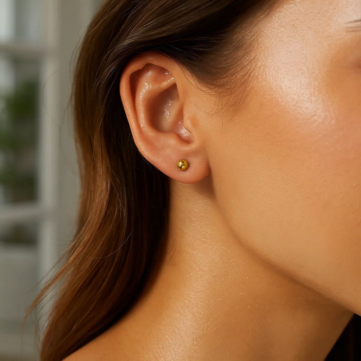 Close-up view of 10k yellow gold 4mm ball stud earring worn on ear
