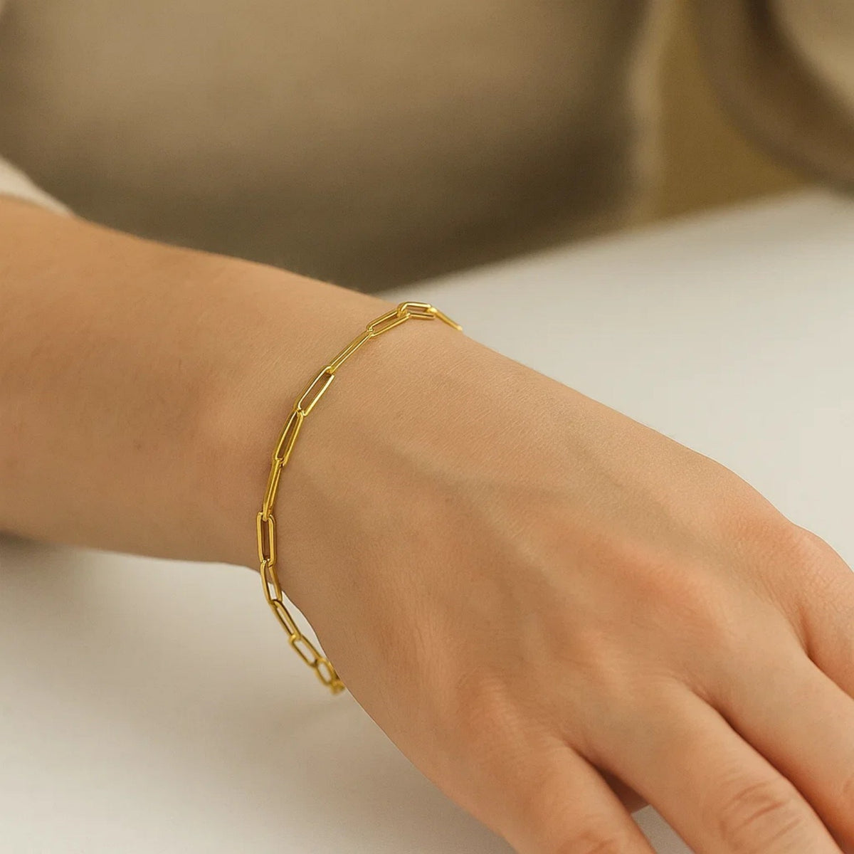 10K yellow gold paperclip bracelet worn on woman's wrist, close-up detail shot showing link texture